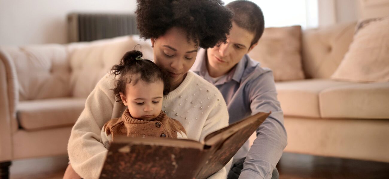 Una foto de una familia leyendo un libro juntos en la sala de estar